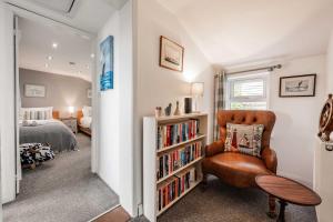 1 dormitorio con estante de libros y silla en Riverside Cottage - Norfolk Holiday Properties en Reedham
