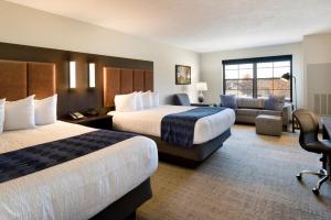 a hotel room with two beds and a couch at ClubHouse Hotel Sioux Falls in Sioux Falls