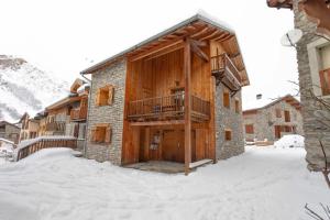 a building with a wooden door in the snow at Chalet Laura in Saint-Marcel