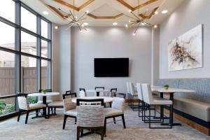 a restaurant with tables and chairs and a flat screen tv at ClubHouse Hotel Sioux Falls in Sioux Falls