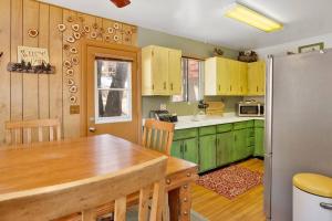a kitchen with green cabinets and a wooden table at Nestled Oaks Cottage~ Bear Mountain Resort Chalet~ in Big Bear Lake