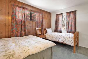 a bedroom with two beds and a window with curtains at Nestled Oaks Cottage~ Bear Mountain Resort Chalet~ in Big Bear Lake