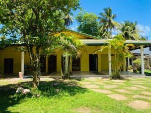 a yellow house with palm trees in front of it at Aramba Resort in Dondra West