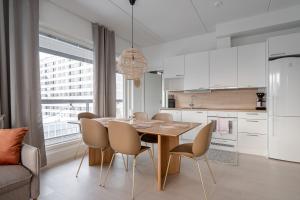 cocina y comedor con mesa de madera y sillas en 2ndhomes Tampere "Sonetti" Apartment - Modern 2BR Apartment with Sauna and Balcony en Tampere
