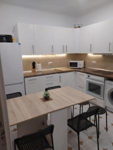 una cocina con armarios blancos y una mesa de madera con sillas. en Amplio apartamento con dos patios y aparcamiento privado en Gijón