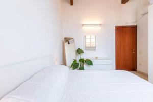 a white bed in a room with a wooden door at Castello Attic Sunset Terrace in Cagliari +53 photos