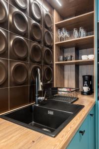 a kitchen with a black sink and wooden cabinets at CLUJSTAYS Urban Nest Central Apartment in Cluj-Napoca