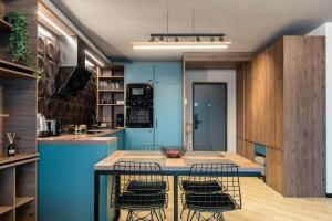 a kitchen with blue cabinets and a table with chairs at CLUJSTAYS Urban Nest Central Apartment in Cluj-Napoca +23 photos
