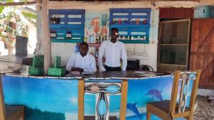 Smile Gambia Beach Bar في بروفوت: اثنين من الرجال واقفين في عداد في بار
