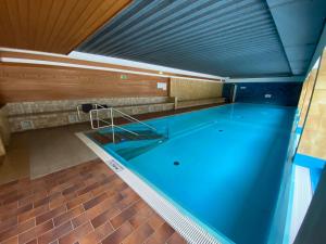 a large swimming pool with blue water in a building at Gerlitzen, Kanzelhöhe, Über den Wolken, Haus Enzian in Deutschberg