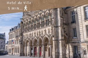 a large stone building with a sign in front of it at Le Fleur de Cerisier - ZMN Conciergerie in Saint-Quentin