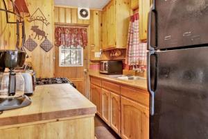 a kitchen with wooden cabinets and a black refrigerator at Bear Paw Cottage~ Hot Tub~ Resort Base Camp Cottage~ in Big Bear Lake