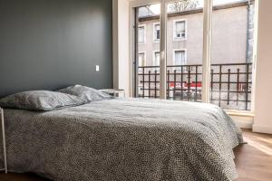 a bedroom with a bed and a large window at T2 Le Miredames in Castres