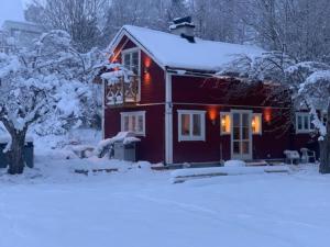 una casa cubierta de nieve con luces encendidas en 1800 tals Sjötorp med egen strand och brygga en Åkersberga