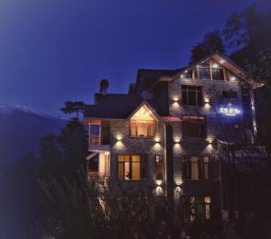 una casa con luces encendidas por la noche en The Bliss Cottage Manali Luxury Apartment and villa, en Manali