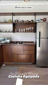 a kitchen with a stainless steel refrigerator and wooden cabinets at Chales Campestre Monte Verde - 150 mts do Centro in Monte Verde