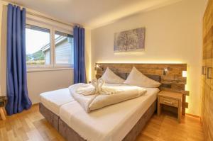 a bedroom with a bed with blue curtains and a window at Golf & Glacier View - by Alpen Apartments in Zell am See