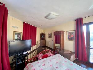 a bedroom with a bed with red curtains and a tv at Residence delle Rose in Barolo