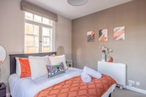 a bedroom with a bed with orange and white pillows at Windsor Castle Chic: 1BR,Parking in Windsor