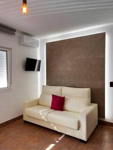 ein Wohnzimmer mit einem weißen Sofa und einem roten Kissen in der Unterkunft La casa de la avenida in Cenes de la Vega