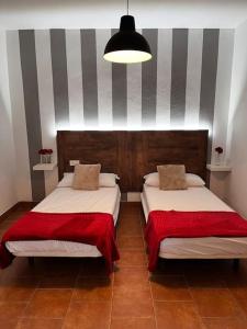1 dormitorio con 2 camas y mantas rojas en La casa de la avenida, en Cenes de la Vega