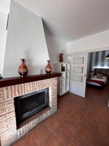 una sala de estar con chimenea de ladrillo y una habitación con cama en La casa de la avenida, en Cenes de la Vega