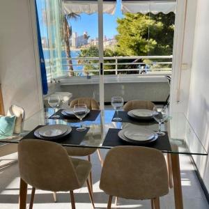 een eettafel met stoelen en een glazen tafel met wijnglazen bij Apto Cala Real Playa Muchavista - ElCampello in Alicante