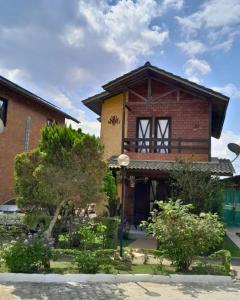 una casa de ladrillo con árboles y arbustos delante de ella en Casa 04 do Condomínio Privê Portal das Flores, en Gravatá