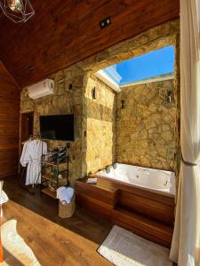 a large bathroom with a tub in a stone wall at Recanto Entre Rios in Bom Jardim da Serra