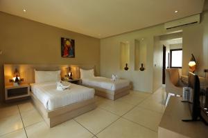 a hotel room with two beds and a television at Living Asia Resort and Spa in Senggigi