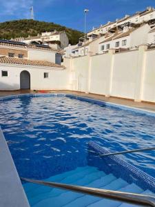 a swimming pool with blue water in front of buildings at Casa con piscina comunitaria en Albayzin alto in Granada