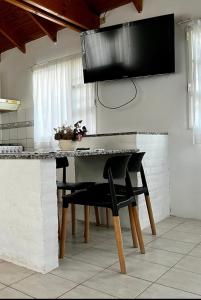 eine Küche mit einem Tisch mit Stühlen und einem TV in der Unterkunft La calma in Puerto Madryn
