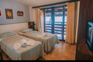 a hotel room with two beds and a television at Pipa's Ocean in Pipa