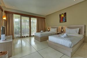 a hotel room with two beds and a television at Living Asia Resort and Spa in Senggigi