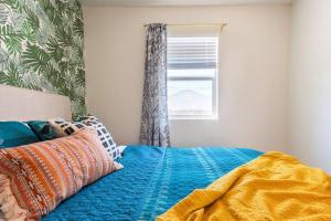 ein Bett mit einer blauen Decke und einem Fenster in der Unterkunft Casita Amarilla, Tiny House in San Diego