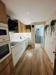 a kitchen with white cabinets and a wooden floor at Premium Aparthotel-PortAventura, FerrariLand,tren in Reus