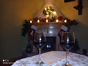 two glasses of wine sitting on a table with a fireplace at Domowe Zacisze w Nickulinie in Rajcza