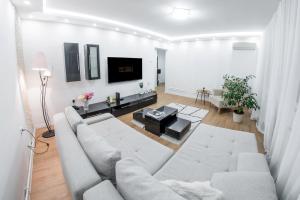 a white living room with a couch and a table at The SKVER-Elegant City Apartmant in Požarevac