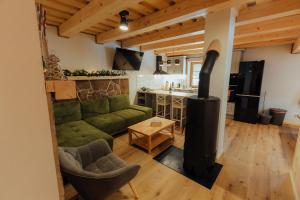 a living room with a green couch and a wood stove at Chata pod Mníchom in Terchová