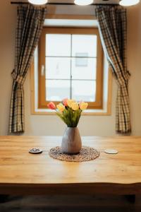 a vase of flowers on a table with a window at Chata pod Mníchom in Terchová