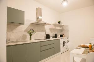 cocina con armarios verdes, lavadora y secadora en A Due Passi, en Montesano Scalo