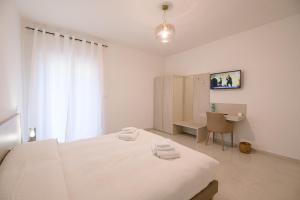 Habitación blanca con cama y escritorio en A Due Passi, en Montesano Scalo
