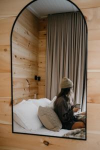 uma mulher sentada numa cama ao espelho em Le 2800 du Parc em Shawinigan