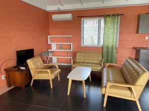 een woonkamer met een bank en stoelen en een tv bij Keris Rental Houses in Vaitele