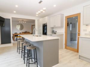 a kitchen with white cabinets and bar stools at White Bull House in Amlwch