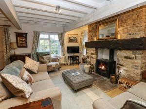 a living room with a fireplace and a stone wall at Malt Shovel Cottage in Bedale