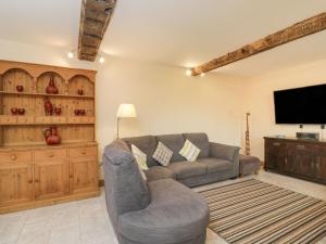 a living room with a couch and a flat screen tv at Chequers Barn in Corsham