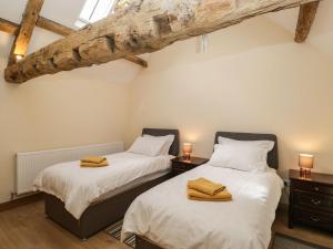 Cette chambre comprend 2 lits jumeaux et des poutres apparentes. dans l'établissement Chequers Barn, à Corsham