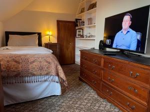 a bedroom with a bed and a flat screen tv on a dresser at Ramadale B&B in Stornoway