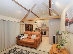 a living room with a brown couch and a kitchen at The Cattle Byre in Corsham